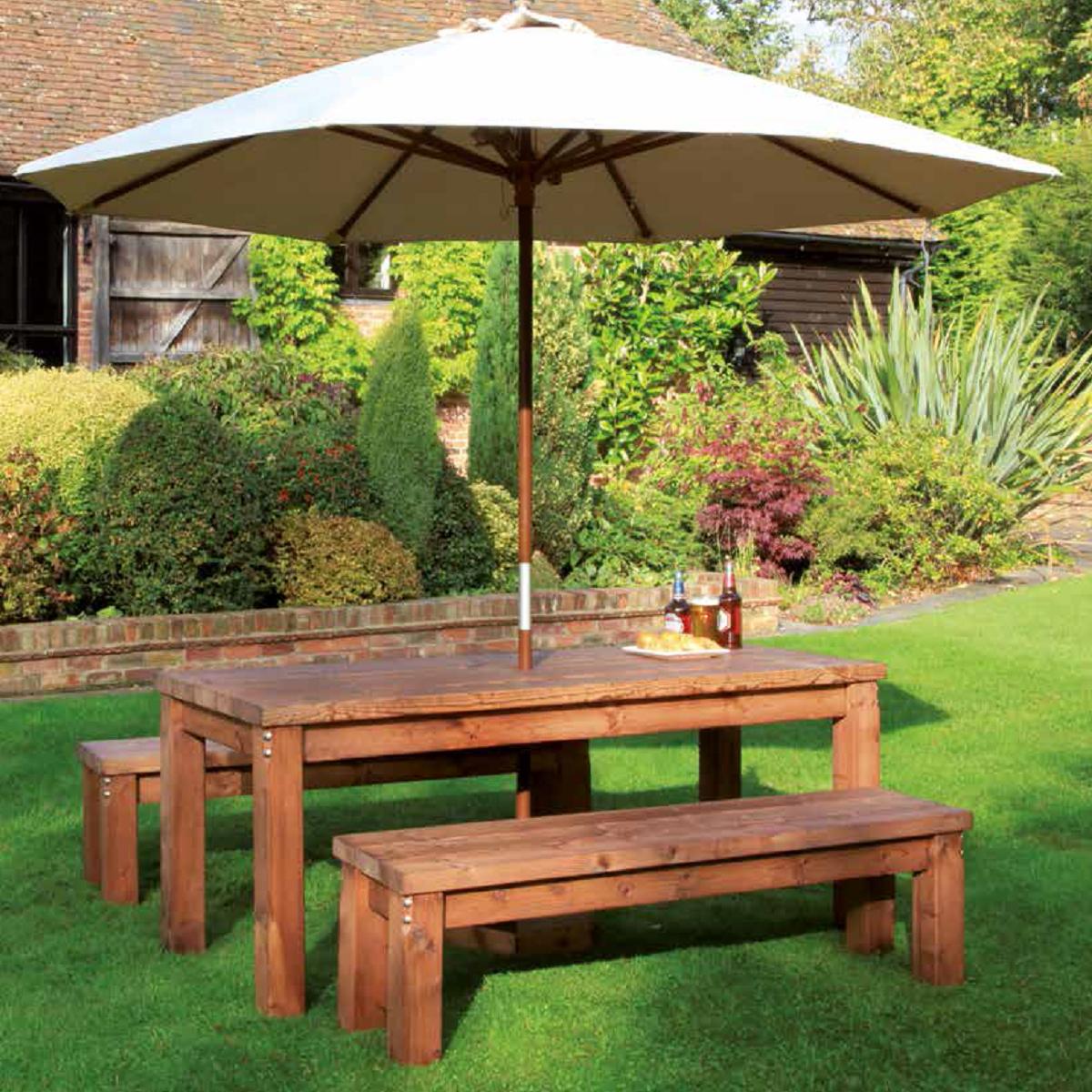 A chunky wooden rectangular table with backless wooden benches either side and a cream parasol