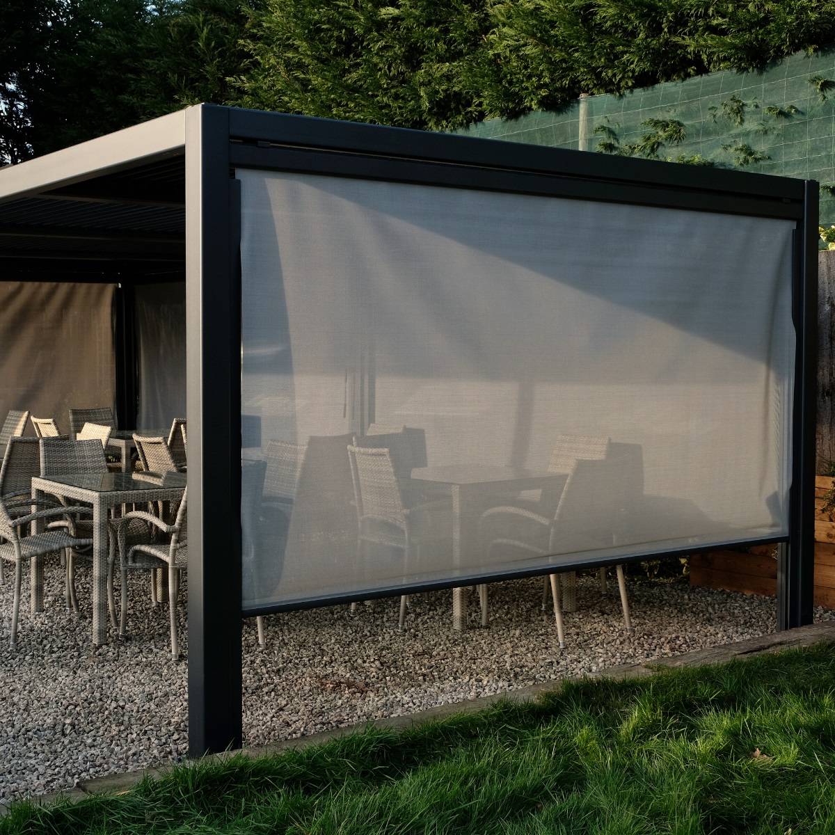 A luxury rectangular grey metal gazebo with rattan dining funiture underneath and a side blind down