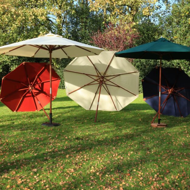 5 parasols in cream, blue, green and terracotta arranged on a lawn