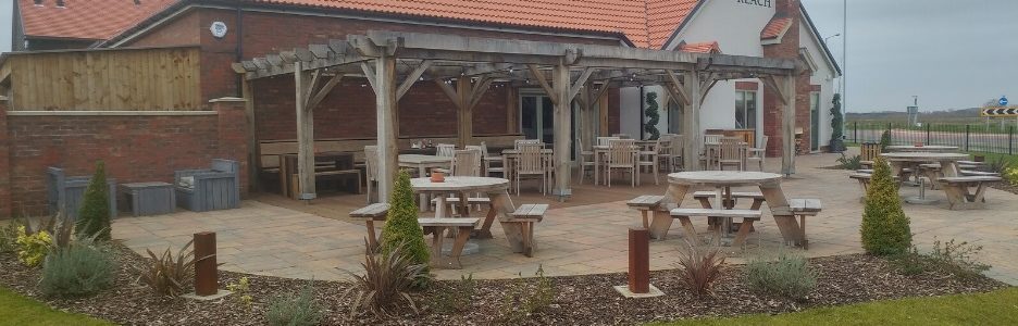 A pub garden patio with spaced out wooden picnic tables for social distancing