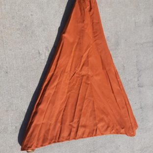 A terracotta canvas canopy for a parasol laid flat on a concrete floor