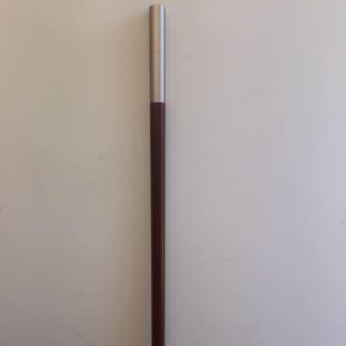 A parasol pole sold as a spare part propped up against a white wall