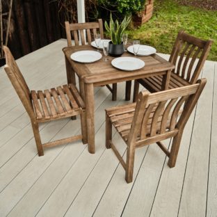 A dark wooden square outdoor table and 4 chairs set with plates and glasses on a garden deck