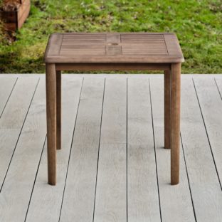 A square hard wood outdoor dining table on a garden deck