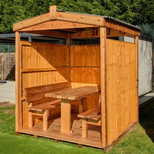 A 6 seater wooden outdoor dining cabin with an apex waterproof roof set on a lawn