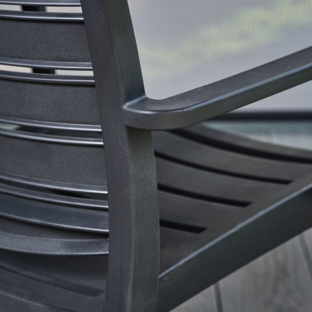 A close up view of the back and arm of a dark grey plastic outdoor dining chair