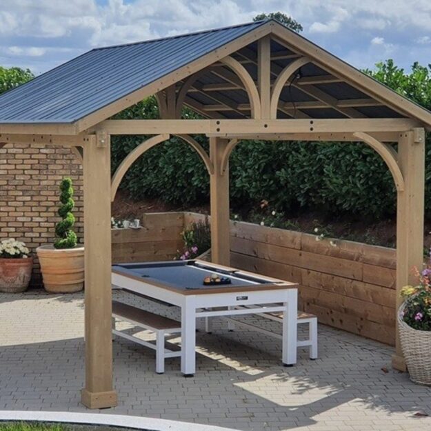 A cedar wood square outdoor gazebo with an apex galvanised steel roof on a patio