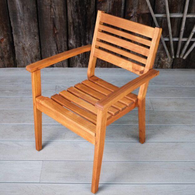A robinia hard wood outdoor dining chair with arms and a slatted seat and back on a deck