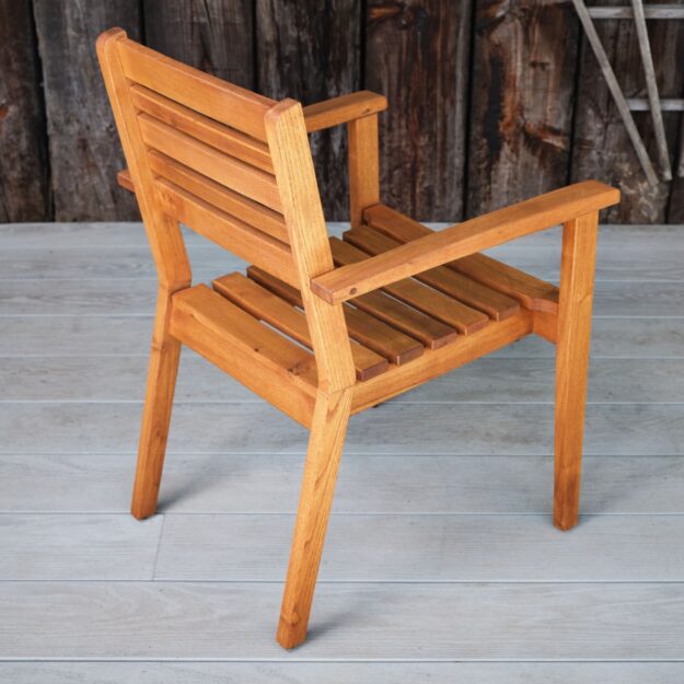 The back view of an outdoor robinia hard wood dining chair with arms on a grey outdoor deck