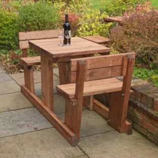 A 2 seater wooden picnic table where the bench seats have backrests loccated on a patio
