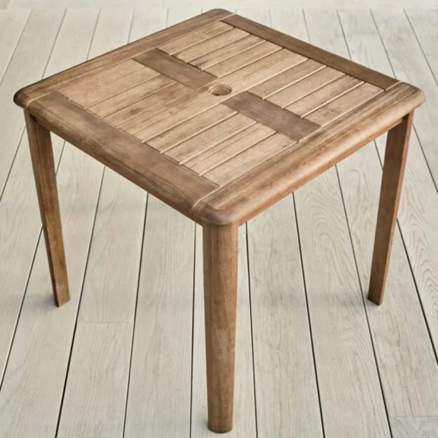 A square hard wood outdoor table with a parasol hole in middle of the table on a garden deck